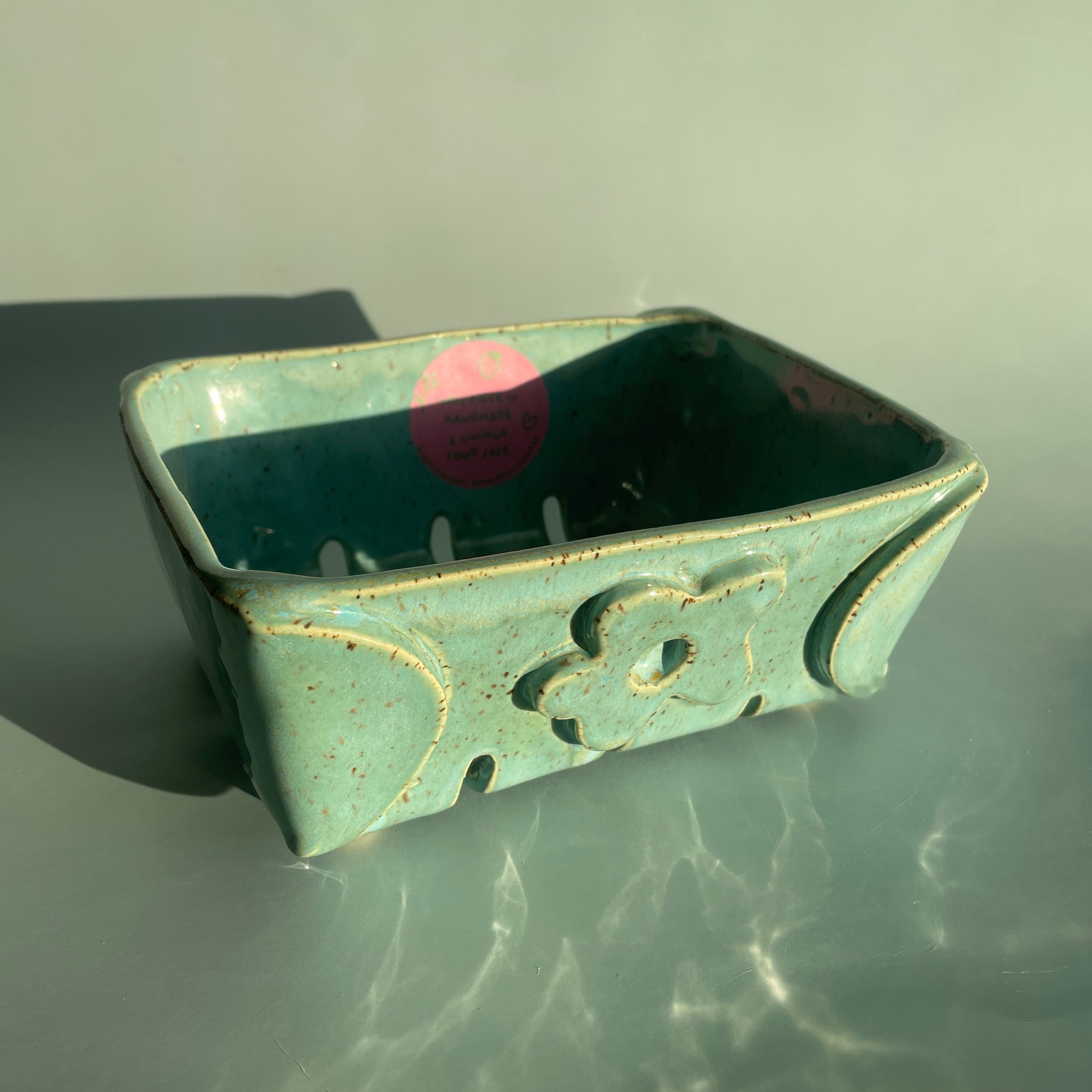 handmade ceramic berry bowl with a green finish and flower detail on the front