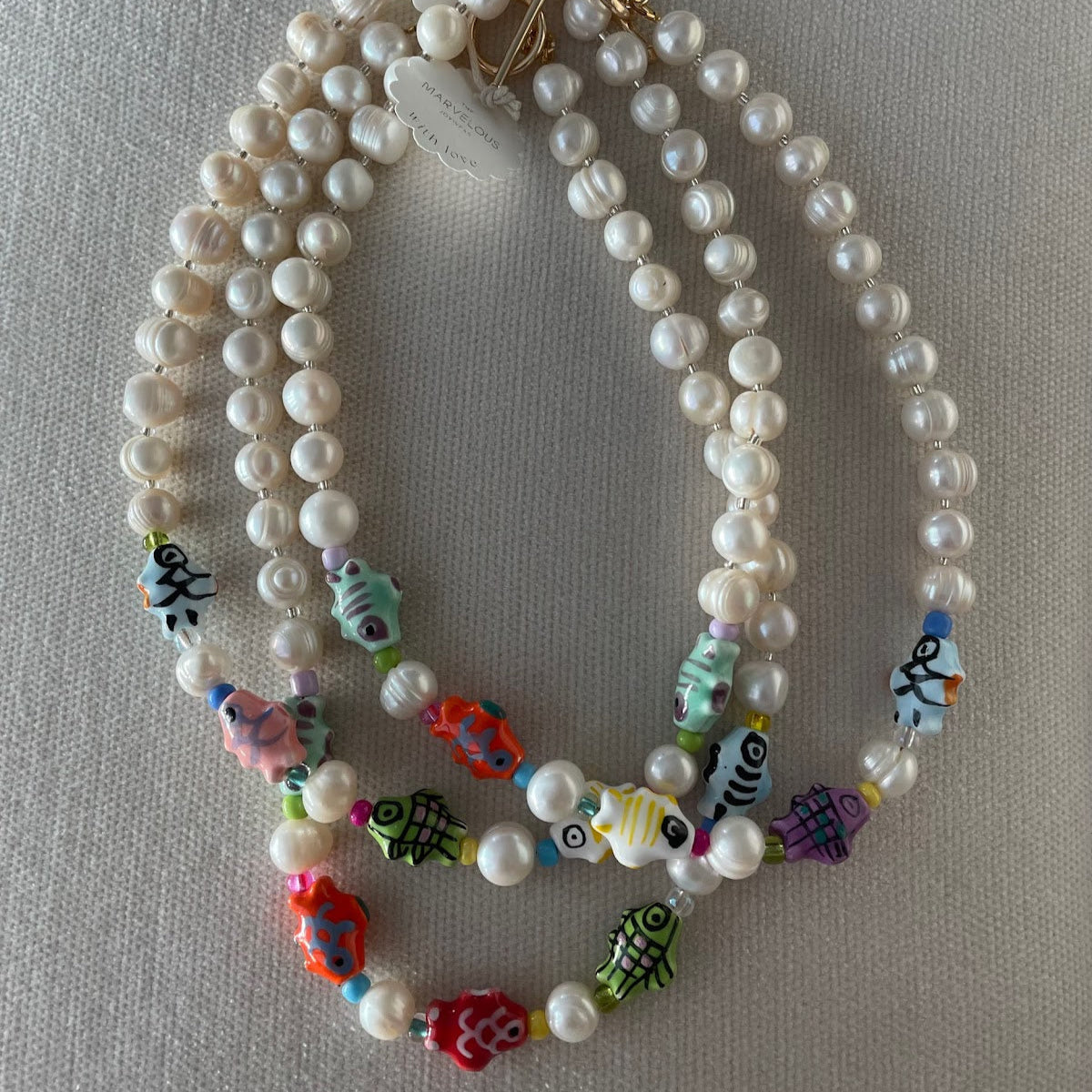 A pearl necklace adorned with happy fish charms. 