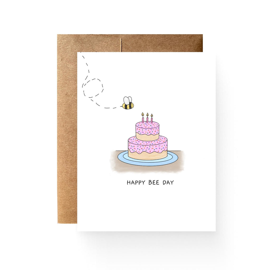 white card with a pink birthday cake and a buzzing bee. reading "happy bee day"