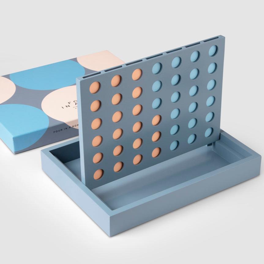 Experience our Play - Four in a Row set, a stylish twist on the classic game, featuring a sober palette and distinct graphics. It is made entirely of lacquered wood, including 42 playing discs (21 of each color), featuring a durable construction that conveniently folds into a compact size.