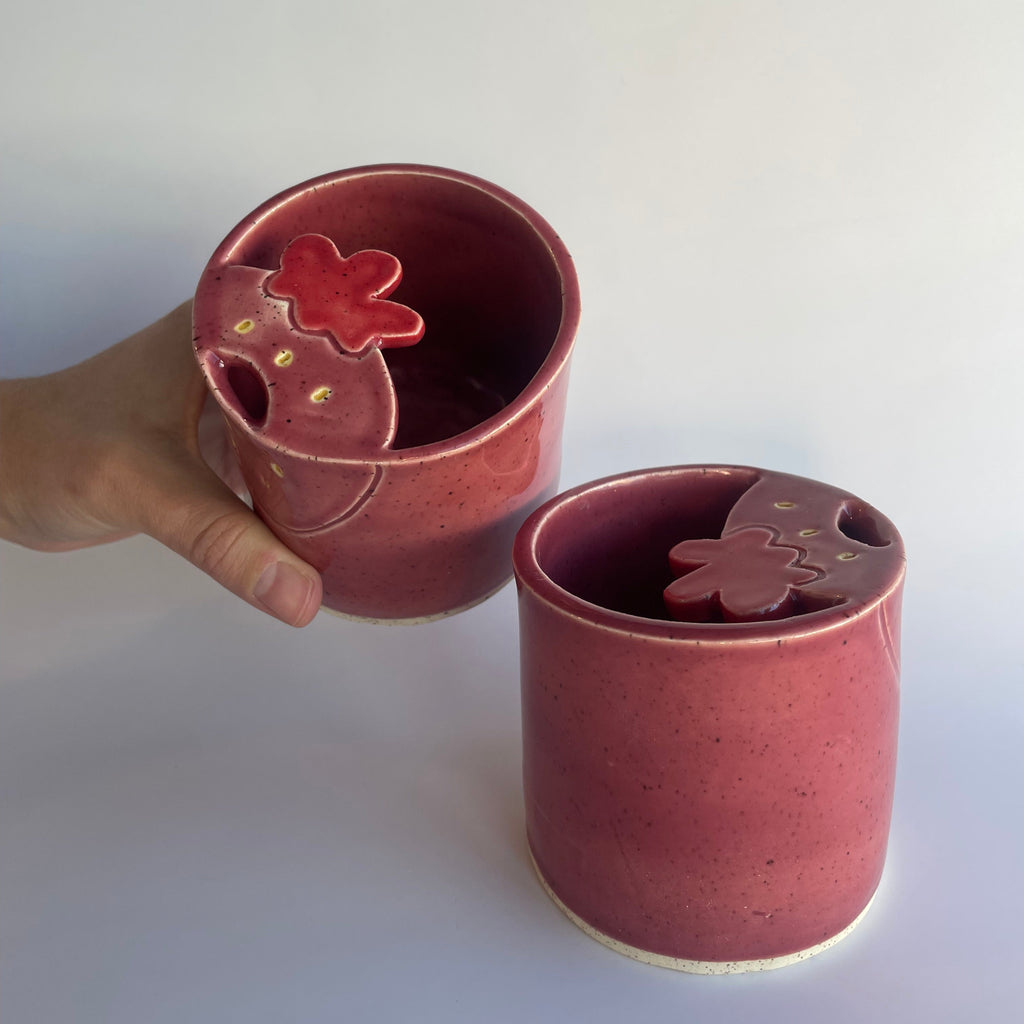 2 pink ceramic travel cups with strawberry shaped sipper tops