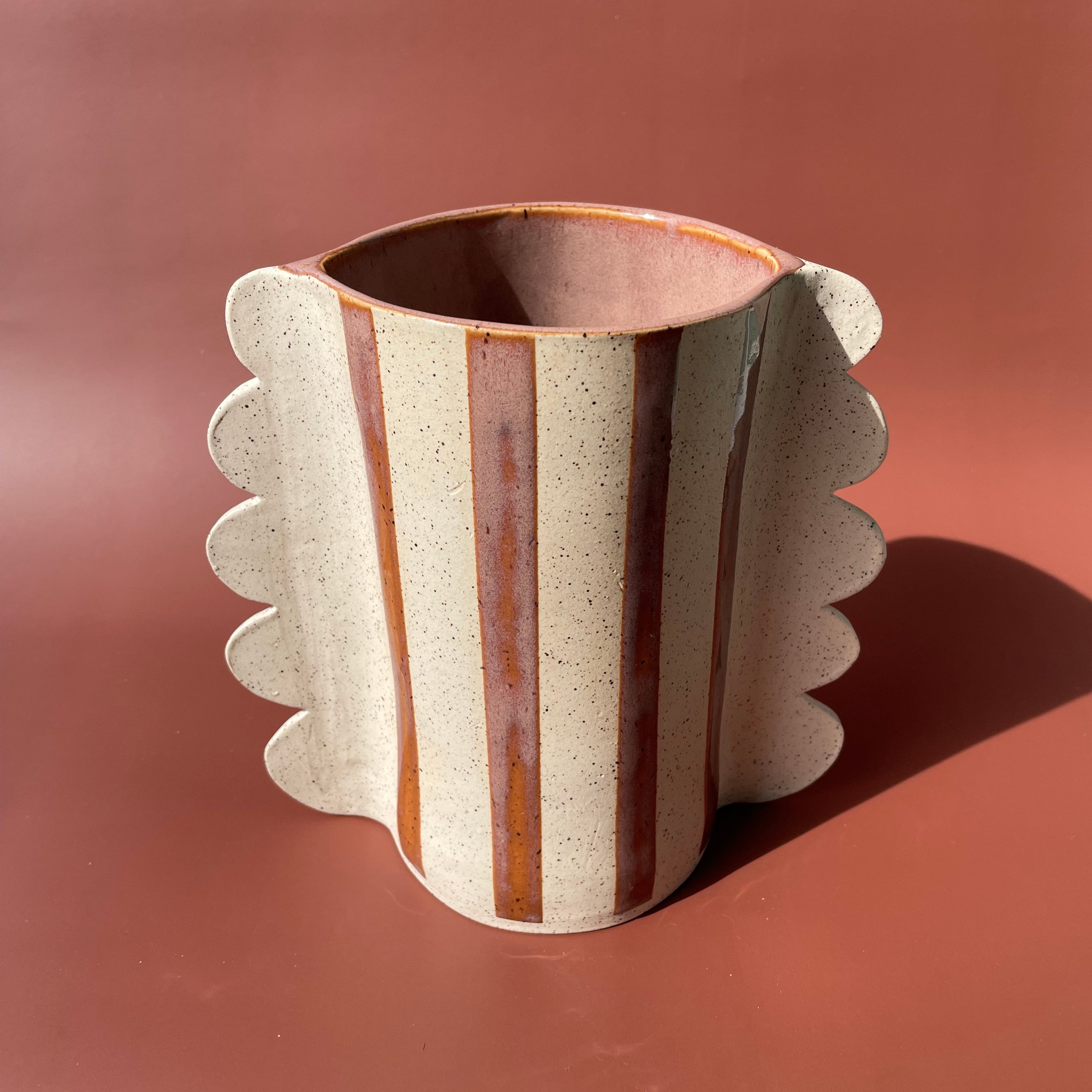 off white ceramic vase with brown specks and orange/brown stripes with scalloped side details