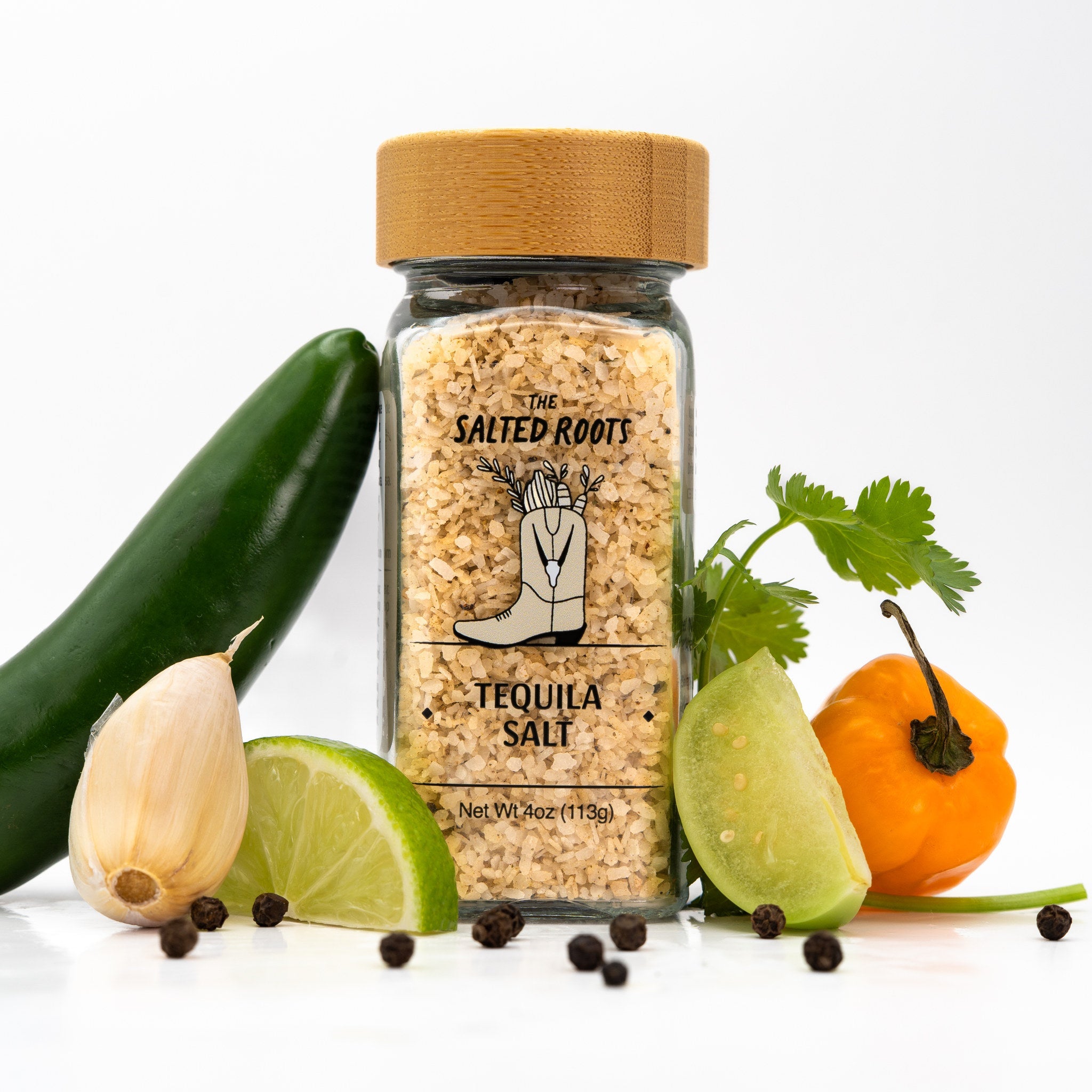 Jar of tequila salt with assorted veggies and herbs scattered around. 