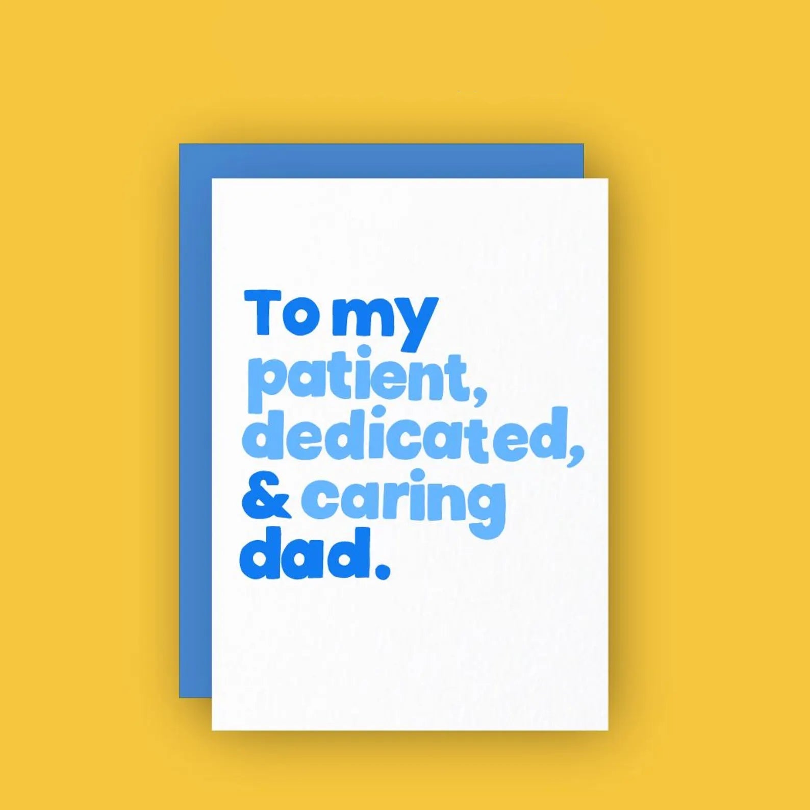 A white greeting card with bold blue letterpress text reads, “To my patient, dedicated, & caring dad.” The card is paired with a blue envelope and set against a bright yellow background for a vibrant, cheerful look.