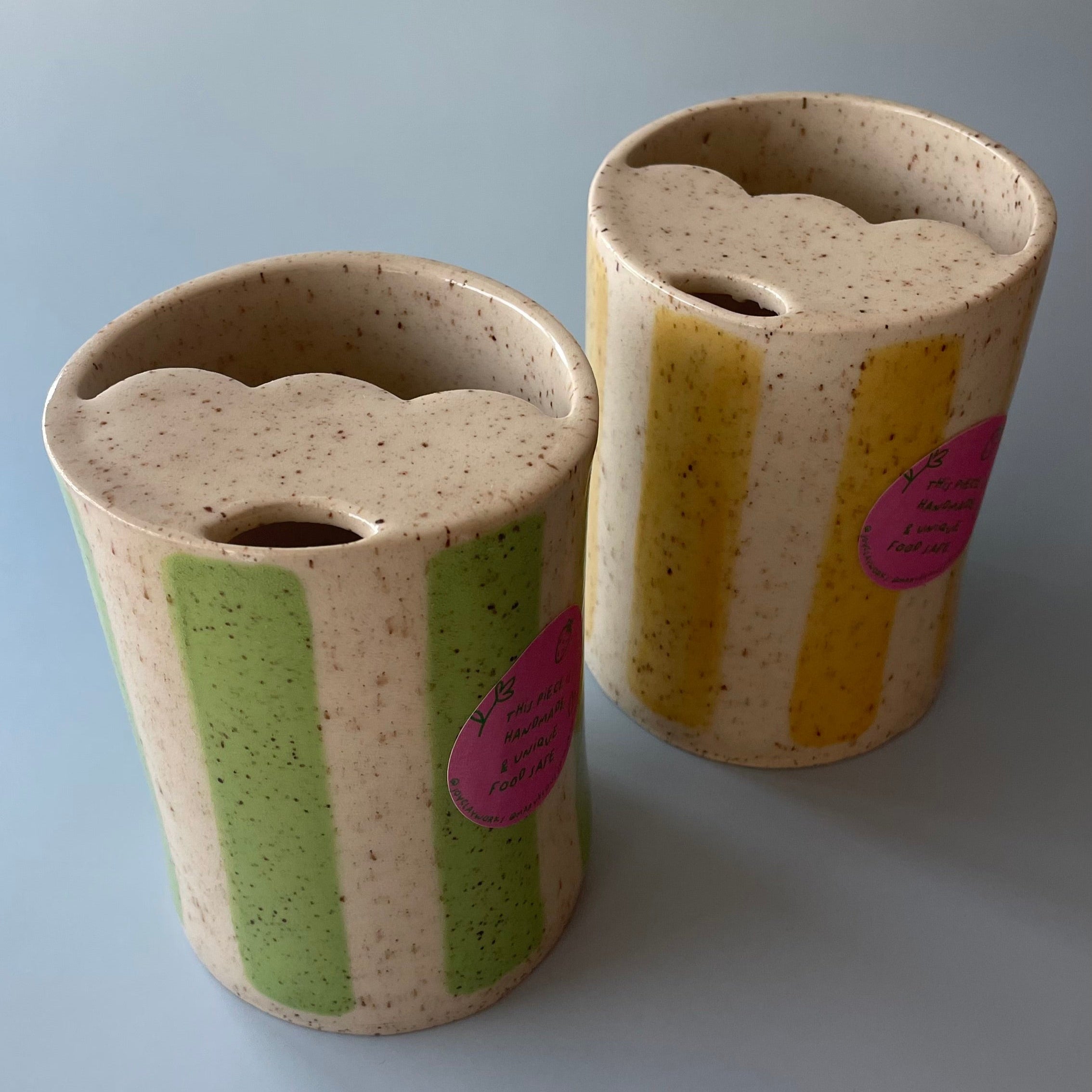 travel mugs with a scalloped lid, and sip hole, glazed with a beige base with brown speckles and comes in either yellow or green striped detail