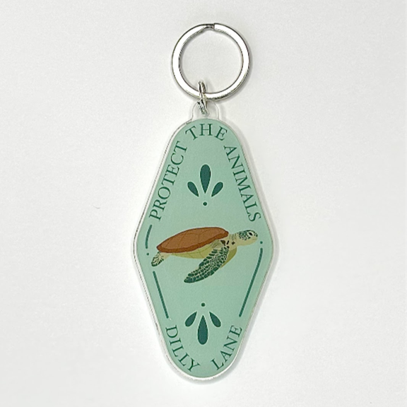 Mint green diamond shaped keychain with a sea turtle. Reading "Protect the animals" and "Dilly Lane"