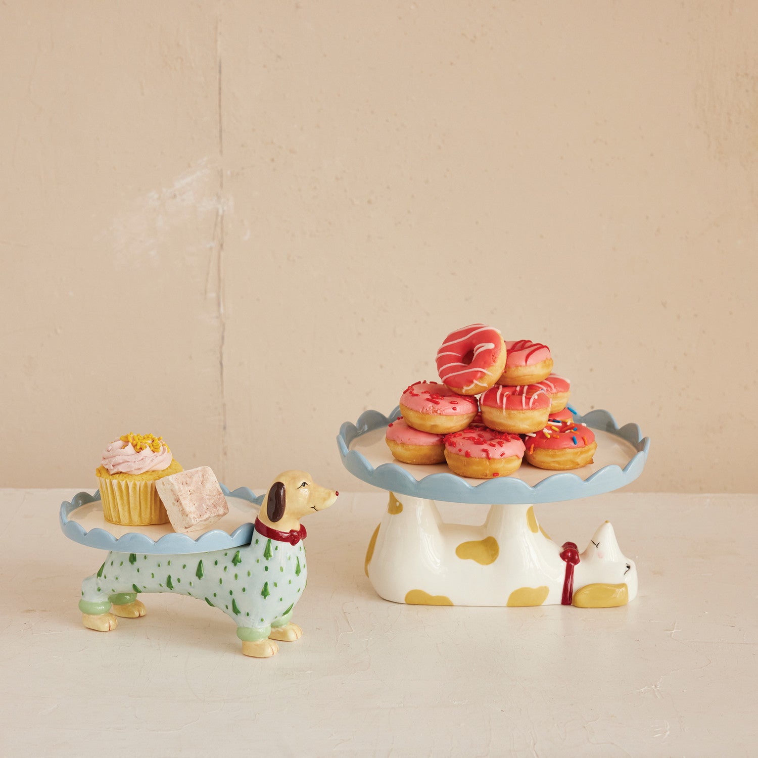Decorative dog-shaped cake stand with a small dog figurine on a beige background