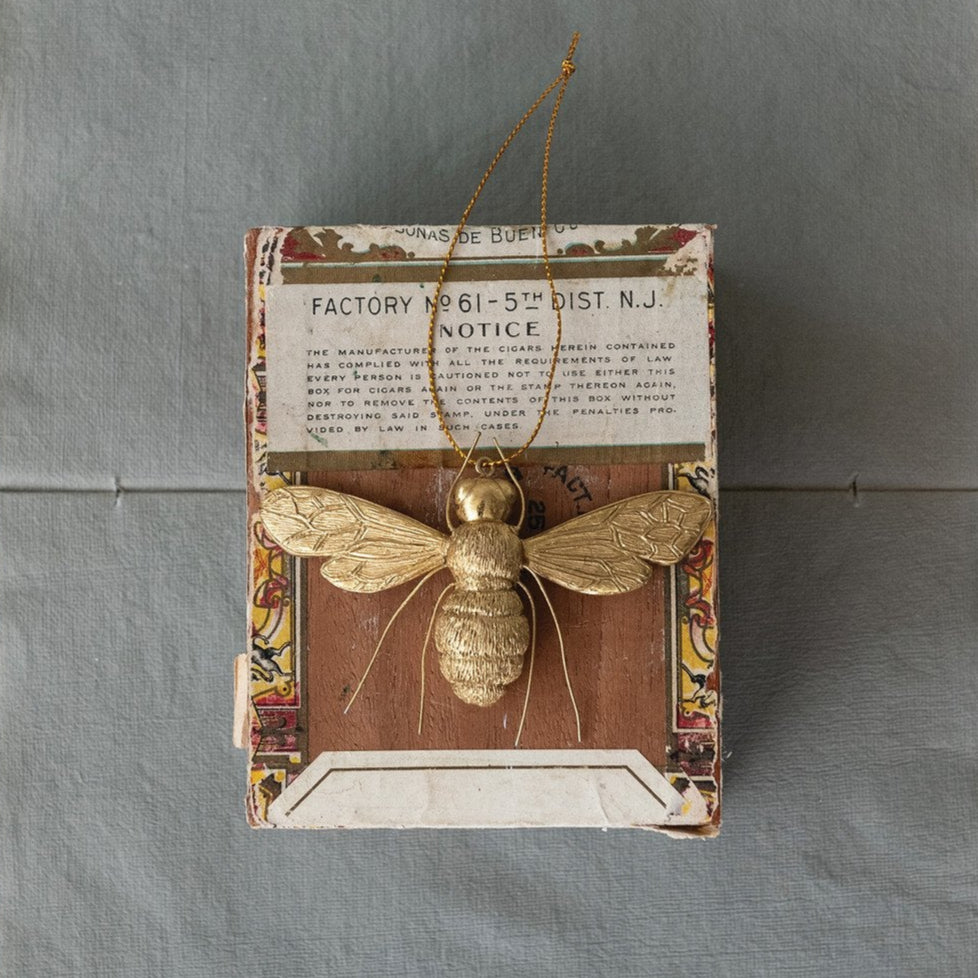 Decorative wall art with a gold bee on an old newspaper background