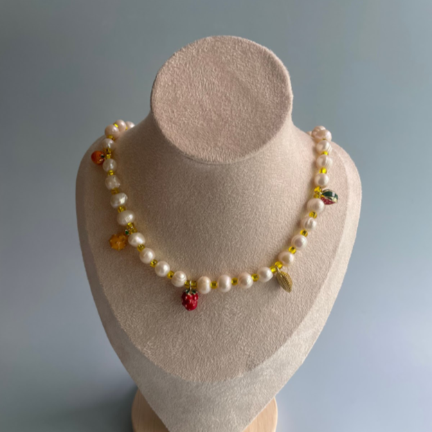 pearl necklace with yellow beads and 5 different fruit charms