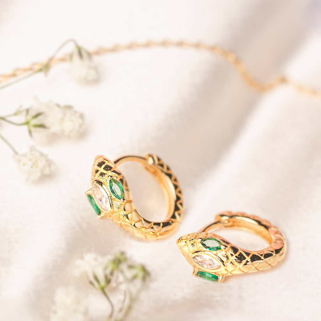 Draco, unusually for constellations, looks exactly like a snake and literally slithers its’ way across the northern sky. It’s located between Ursa Major and Ursa Minor, so it’s easy to spot on a clear night. These serpentine hoops have emerald eyes and a sparkling clear cz on the top, shimmering and slithering their way into our favorite hoops spot.



• 925 sterling silver with gold plating

• Extra layer of tarnish resistance

• Emerald and clear cz textured pattern
