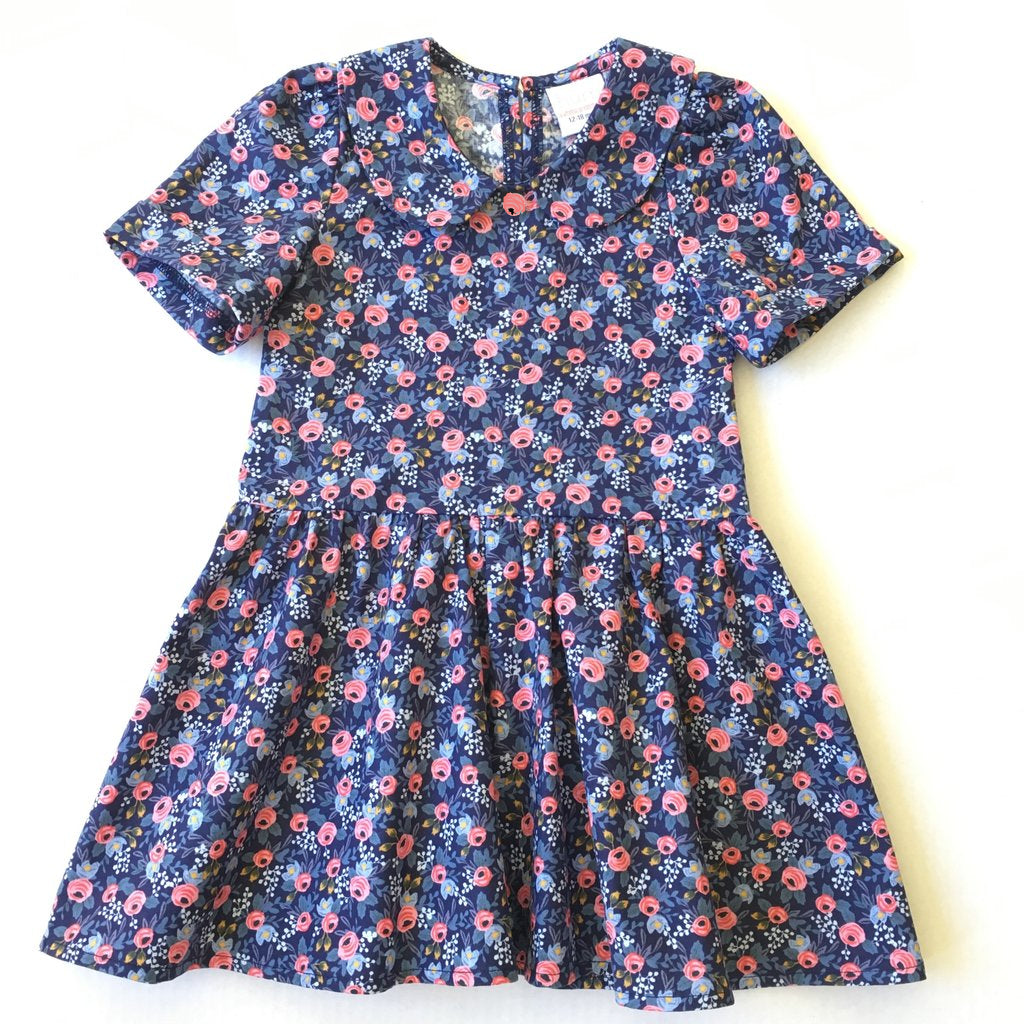 A short-sleeved floral dress in blue and pink with a button at the top and a tie waist.
