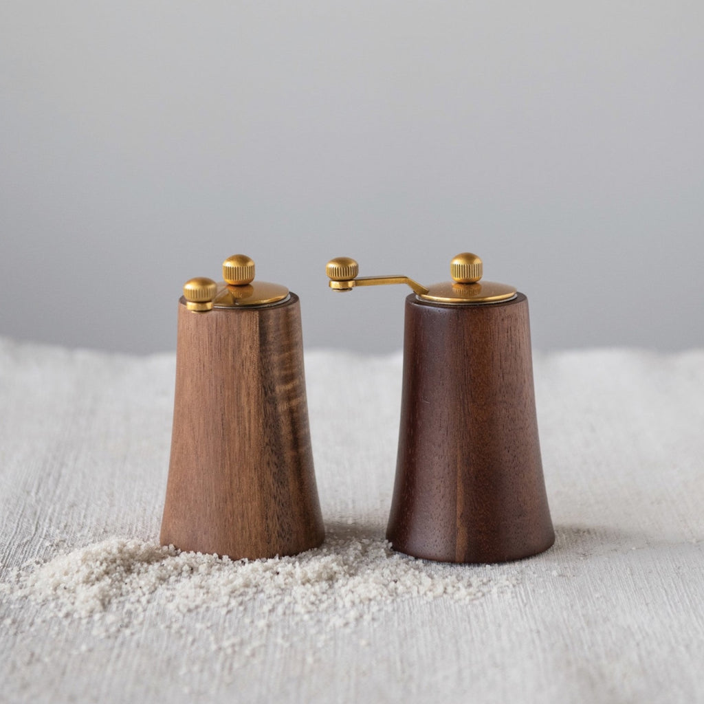 These salt and pepper mills are both sleek and stylish. Made out of acacia wood, these salt and pepper mills have a gold finish that both blend in with any decor styles, and stand out amongst regular salt and pepper shakers.     Dimensions  4-3/4"H  Acacia Wood & Stainless Steel Salt & Pepper Mills, Gold Finish & Natural