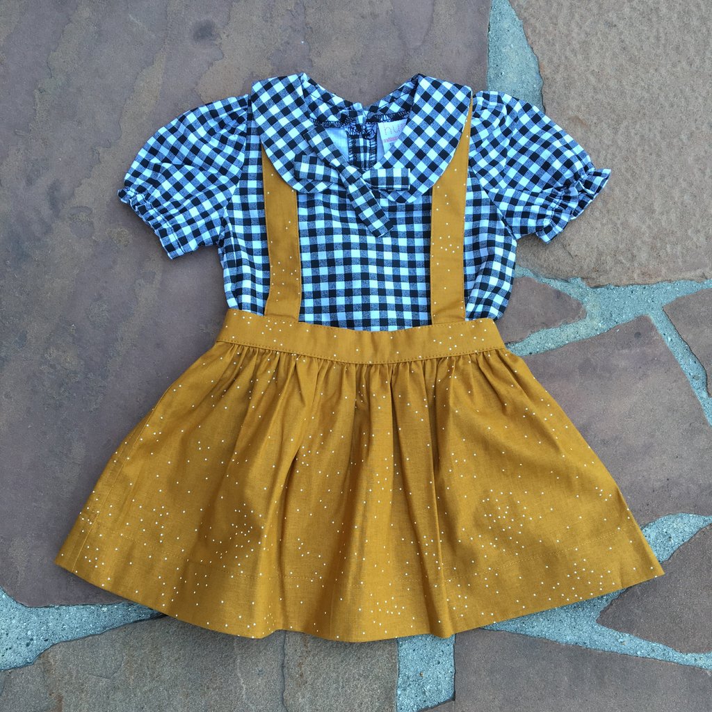 The Andi mini trouser skirt in dark mustard dots has adjustable suspenders with a button on the back. Two button holes are sewn on each suspender strap so your child can grow with their skirt making it easy to wear high on her waist when they are younger & then on their natural waist when older.  This is a shorter skirt that hits above the knee.