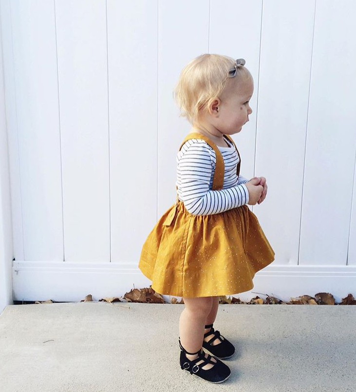 The Andi mini trouser skirt in dark mustard dots has adjustable suspenders with a button on the back. Two button holes are sewn on each suspender strap so your child can grow with their skirt making it easy to wear high on her waist when they are younger & then on their natural waist when older.  This is a shorter skirt that hits above the knee.