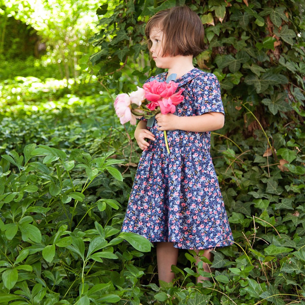 A short-sleeved floral dress in blue and pink with a button at the top and a tie waist.